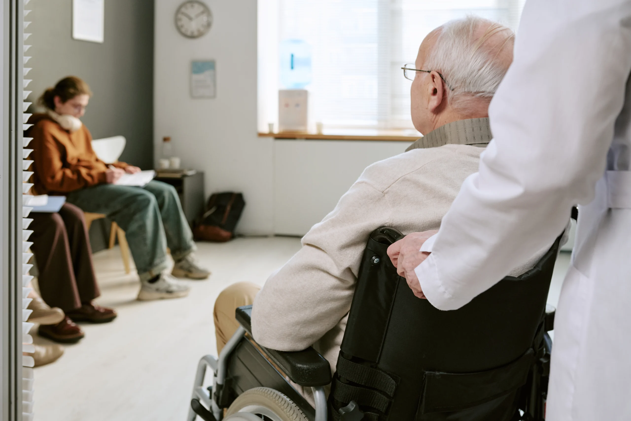 Senior Man with Disability Entering Medical Waiting Room with Doctor